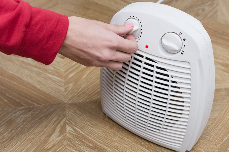 person turning a heater on