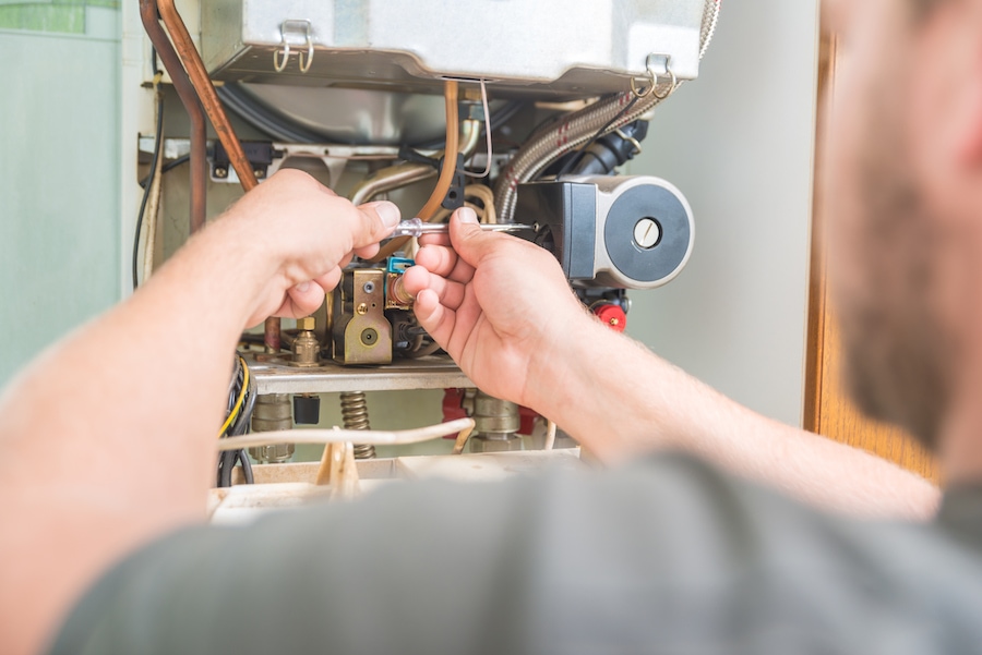 Technician performing fall maintenance on a furnace