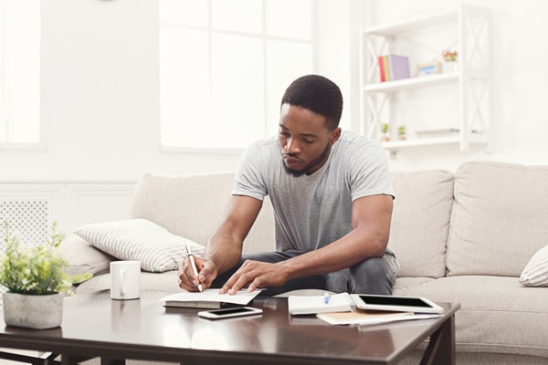 Concentrated young black man preparing for exams at home on couch, copy space in Pasadena, TX