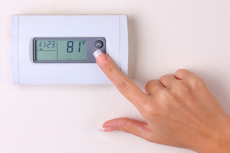 Image of someone using a thermostat. How to Set Your Programmable Thermostat.