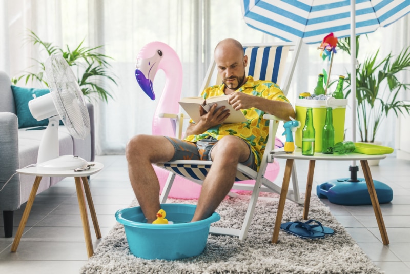 Man sitting in beach chair inside home, reading about Pasadena residential HVAC replacement services.