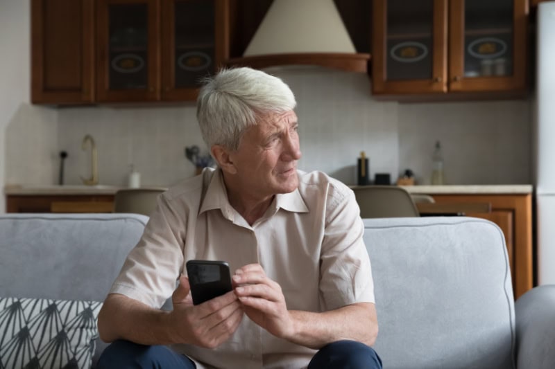 What’s That Smell Coming From My Furnace? Photo of a man sitting on his couch and looking outside of a window, seemingly concerned.